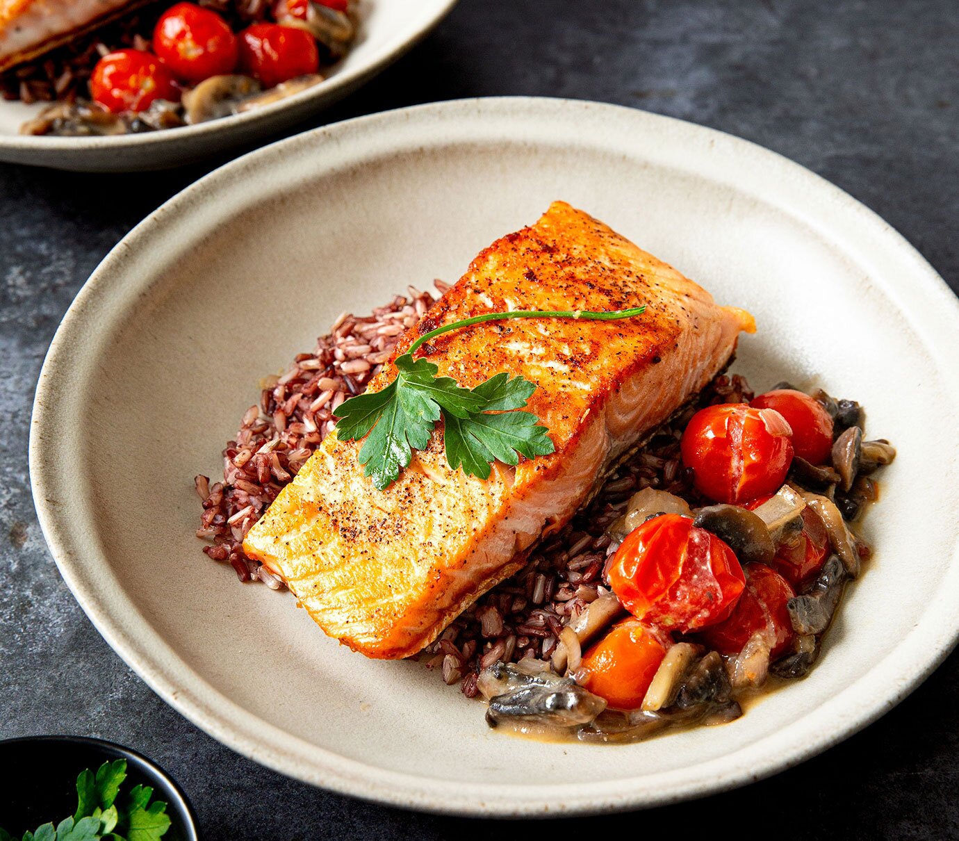 Pan-seared salmon in a miso-butter glaze with sauteed mushrooms and blistered cherry tomatoes, served over wild rice. 