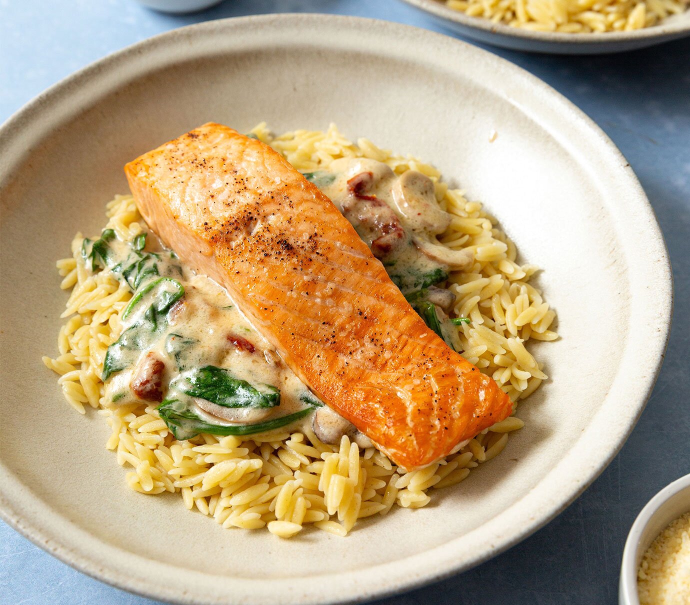 Air-fried salmon over a bed of orzo and a rich creamy sauce, with mushrooms and sundried tomatoes. 