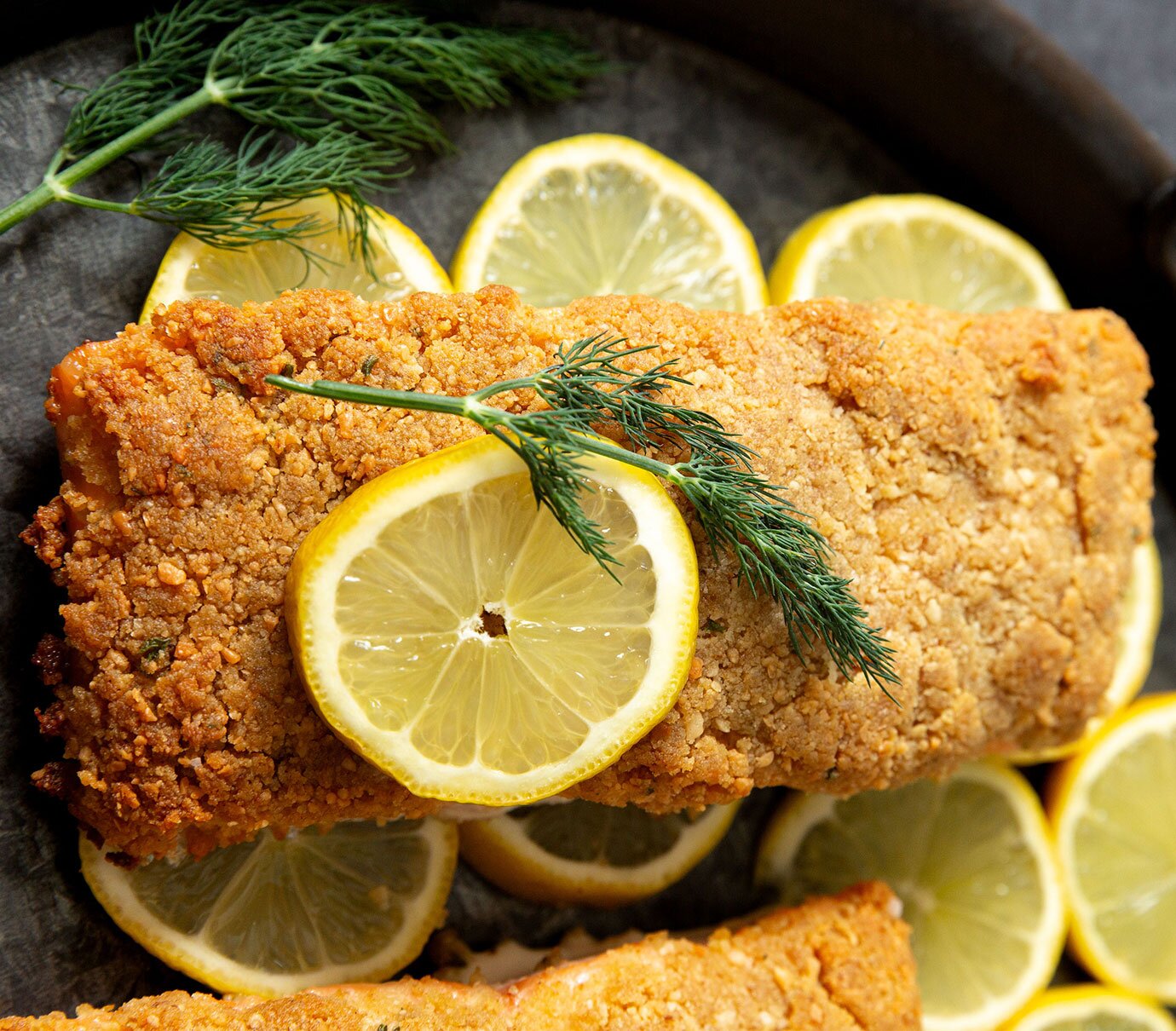 Salmon fillets topped with golden-brown breadcrumbs served with lemon wedges. 